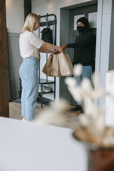 Man in White Shirt and Blue Denim Jeans Holding Brown Paper Bag